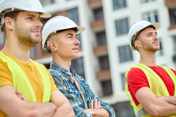 Tres trabajadores de la construcción bien enfocados mirando algo —  Fotos de Stock
