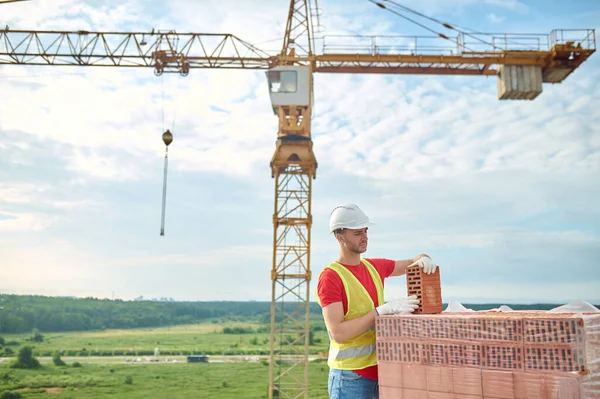 Constructor experimentado en guantes de algodón comprobando la calidad de los materiales de construcción —  Fotos de Stock