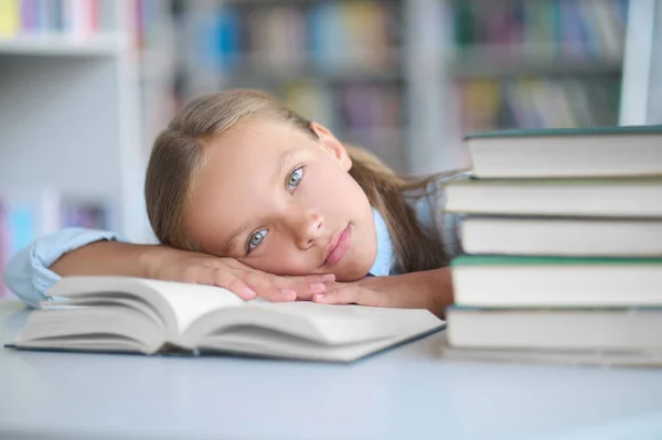 Exhausted schoolchild lying on her library textbook — Stock Photo, Image