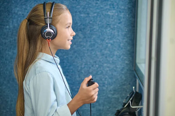 Menina sorridente em fones de ouvido na sala audiométrica — Fotografia de Stock