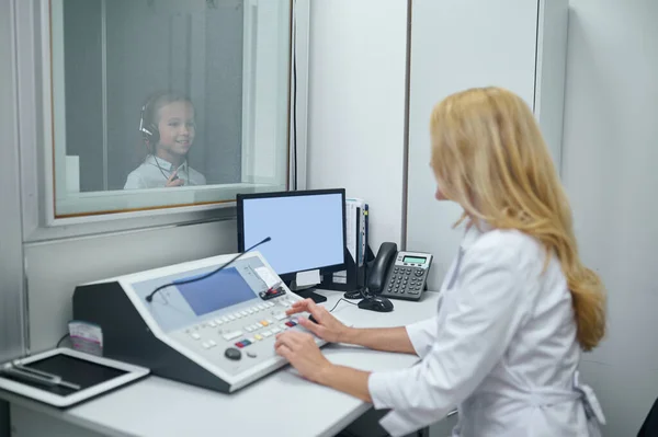 Chica en auriculares de pie en la cabina insonorizada — Foto de Stock