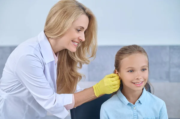 Audiólogo profesional que pone un audífono en el oído de las niñas — Foto de Stock