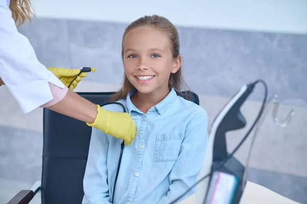 Chica agradable sonriendo a la cámara antes de la comprobación de la audición —  Fotos de Stock