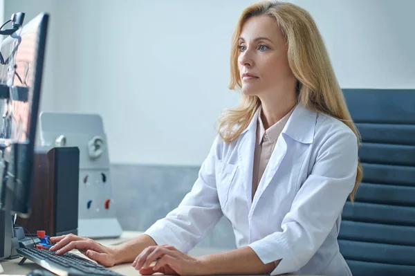 Médico loira bonita focada em verificar seu e-mail — Fotografia de Stock