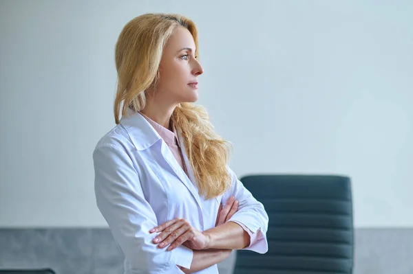 Pensive klidná dáma lékař stojící sám ve své kanceláři — Stock fotografie
