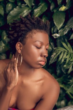 Gözleri kapalı, çıplak omuzlu Afrikalı Amerikalı bir kadın.