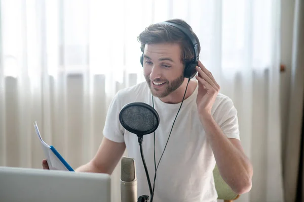 Young bearded man sitting in headphones and speaking in microphone — Stock Photo, Image