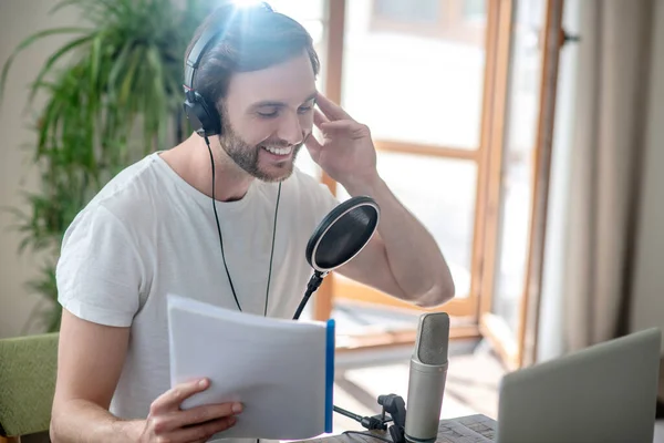 Junger bärtiger Mann sitzt mit Kopfhörern und spricht in Mikrofon — Stockfoto