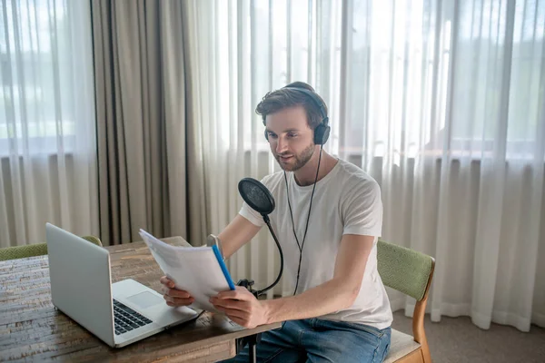 Young bearded man sitting in headphones and speaking in microphone — Stock Photo, Image