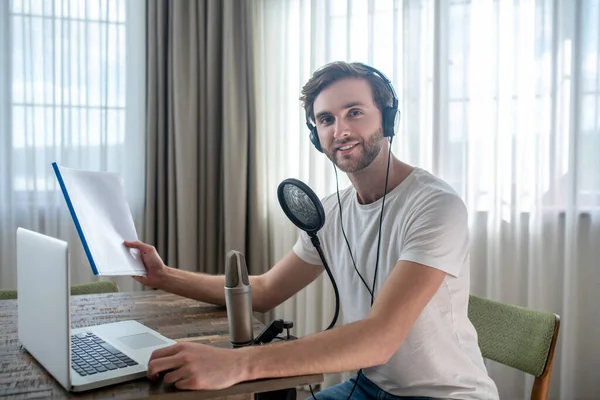 Young bearded man sitting in headphones and having an audio conference — Stock Photo, Image