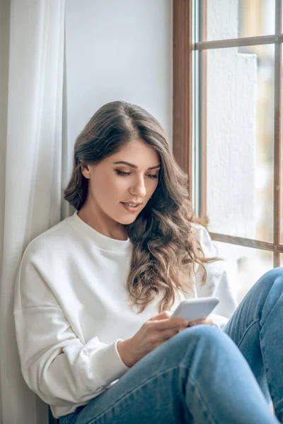 Mladá žena v bílé blůze a džíny s smartphonem — Stock fotografie