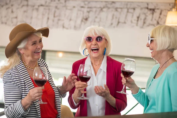 Tre äldre glada damer som har fest och ser njöt medan du dricker vin — Stockfoto