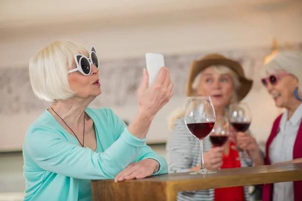 Drei glückliche Seniorinnen haben Spaß und trinken Wein — Stockfoto