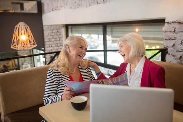 Twee blonde oudere dames zitten aan de laptop en kijken betrokken — Stockfoto