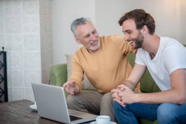 Genç bir adam ve babası internetten bir şeyler izliyor.