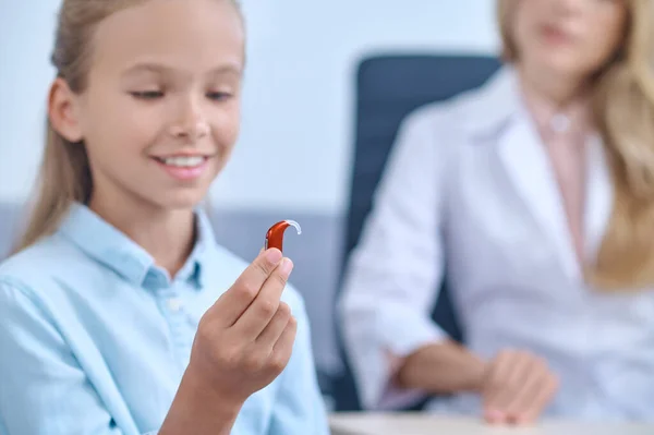 Joyful menina em idade escolar com aparelho de escuta na mão — Fotografia de Stock