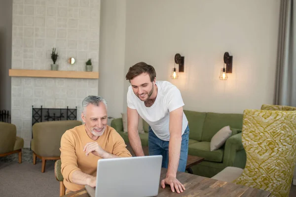 Två män i rummet på laptopen tittar på något på en bärbar dator — Stockfoto