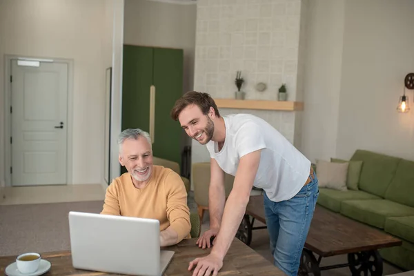 Deux hommes dans la pièce à l'ordinateur portable regardant quelque chose sur un ordinateur portable — Photo