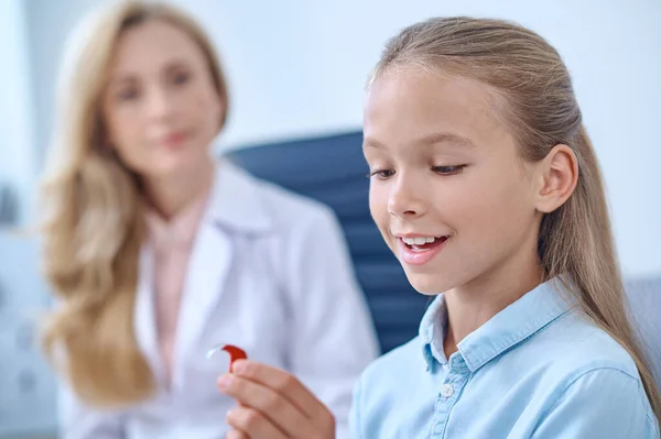 Menina idade da escola feliz admirando aparelho auditivo — Fotografia de Stock