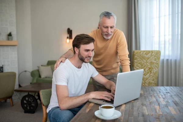 Dos hombres viendo algo en un portátil y mirando involucrados — Foto de Stock