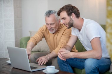 Genç bir adam ve babası internetten bir şeyler izliyor.