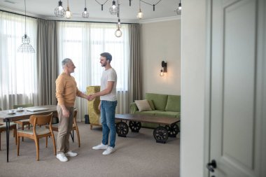 Genç bir adam ve olgun bir adam el sıkışıyor.