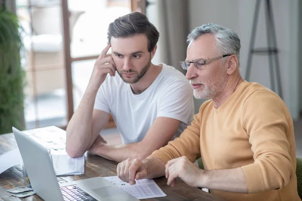 Två män sitter nat bordet och arbetar på en bärbar dator — Stockfoto