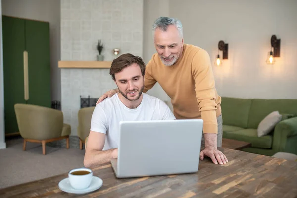 Двоє чоловіків дивляться щось на ноутбук і дивляться задіяні — стокове фото
