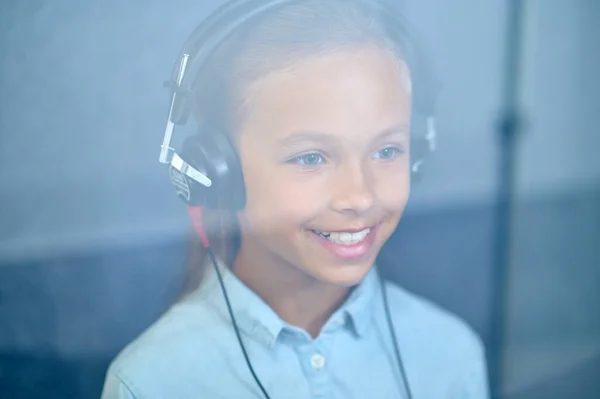 Szczęśliwa dziewczyna w słuchawkach za szybą — Zdjęcie stockowe