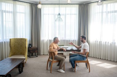 Bir oğul ve bir baba konuşuyor ve çay içiyorlar.