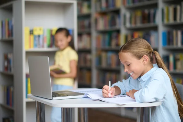 Menina com uma caneta e seu colega de classe com um livro — Fotografia de Stock