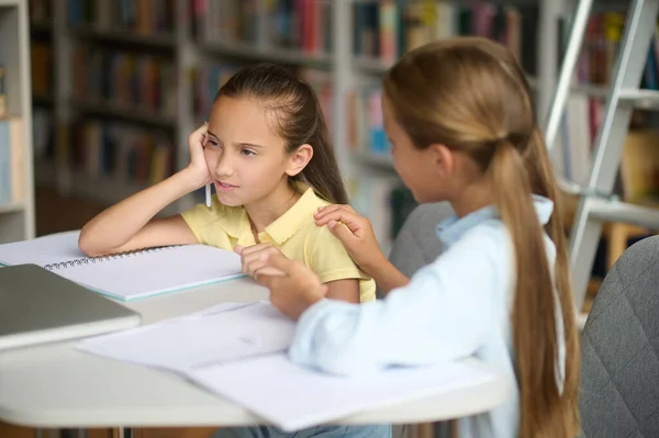 Basso spirito esausto studentessa al tavolo consolato dalla sua compagna di classe — Foto Stock