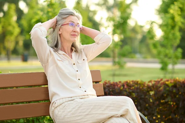 落ち着いた女性が公園のベンチで休んでいる — ストック写真