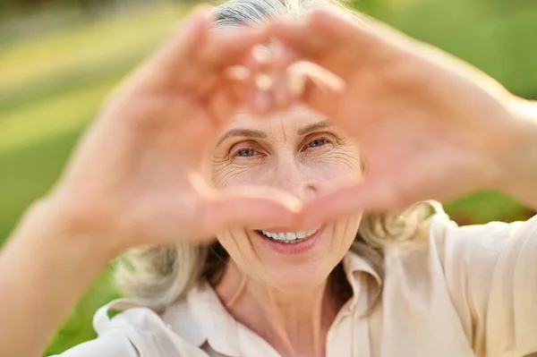 Szczęśliwa kobieta patrząc przez znak serca — Zdjęcie stockowe