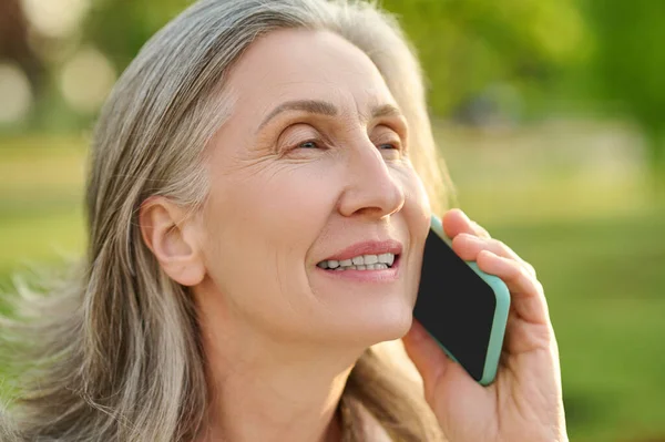 Emeklilik yaşındaki bir kadının akıllı telefondan konuşması. — Stok fotoğraf