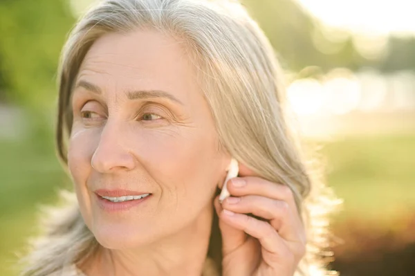 Mujer tocando auriculares inalámbricos en el oído —  Fotos de Stock