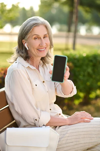 Kulaklıklı kadın akıllı telefon ekranı gösteriyor — Stok fotoğraf