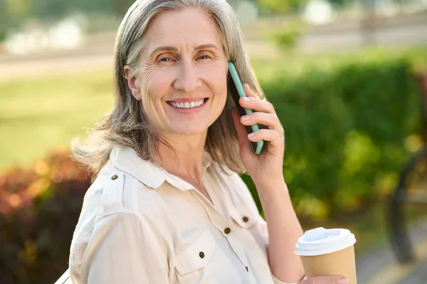 Akıllı telefondan iletişim kuran sevimli, güler yüzlü bir kadın. — Stok fotoğraf