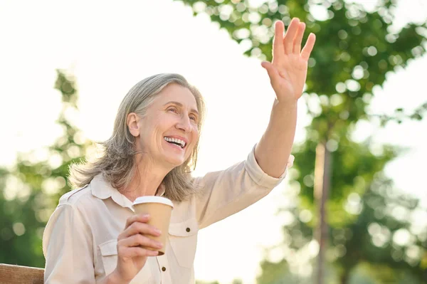 Mulher alegre com saudação café gesticulando com a mão — Fotografia de Stock