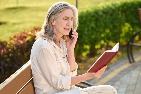 Defterli kadın akıllı telefondan konuşuyor. — Stok fotoğraf