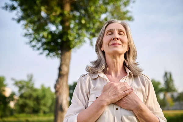 Gelukkig vrouw gevouwen handen op haar borst — Stockfoto