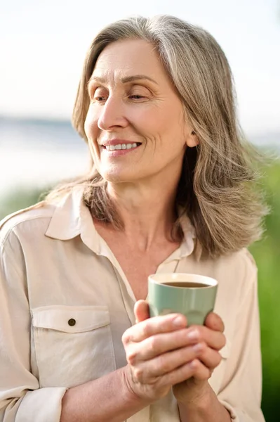 Femme pensive avec café dans la nature — Photo