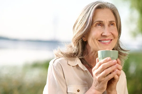 Optimistisch lachende vrouw met koffie buiten — Stockfoto