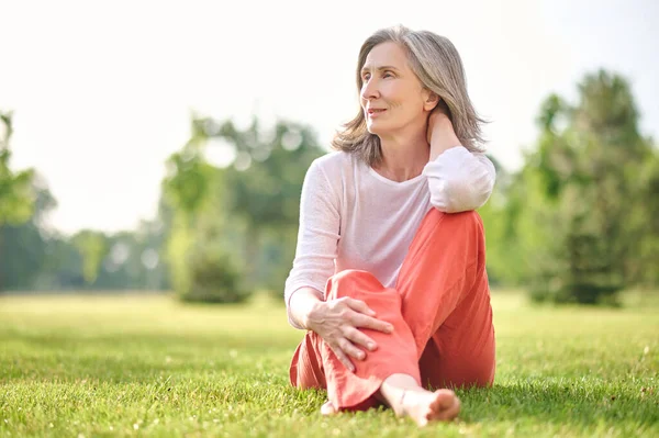 Mujer bonita adulta meditando en el césped en el parque — Foto de Stock