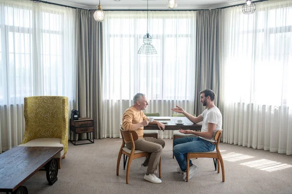 Bir oğul ve bir baba konuşuyor ve çay içiyorlar.