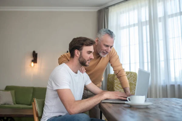 Två män tittar på något på en bärbar dator och ser inblandade — Stockfoto