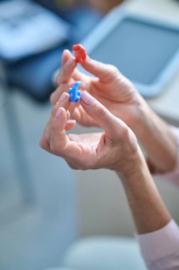 Kadın ellerinde iki işitme cihazı.