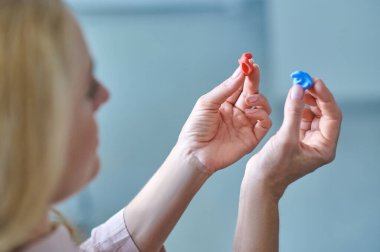 Elinde iki işitme cihazı tutan kadın.