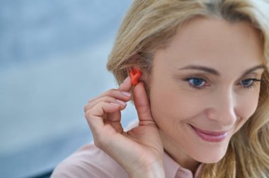 Smiling woman with hearing aid near ear clipart