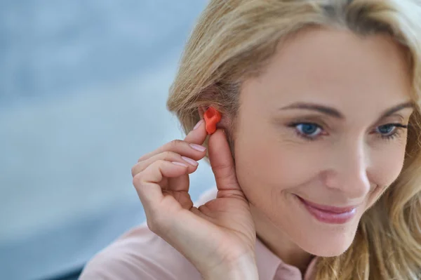 Mulher sorridente com aparelho auditivo perto da orelha — Fotografia de Stock